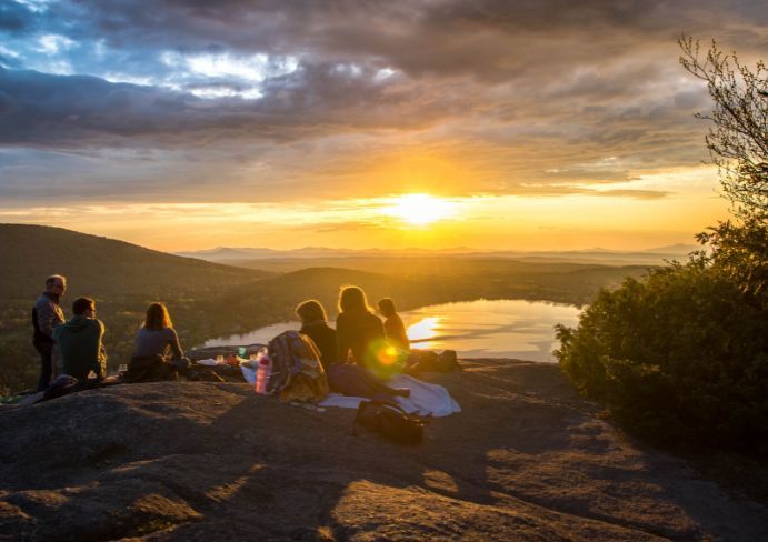 The family is sitting on the edge of the mountain and admiring the sunset